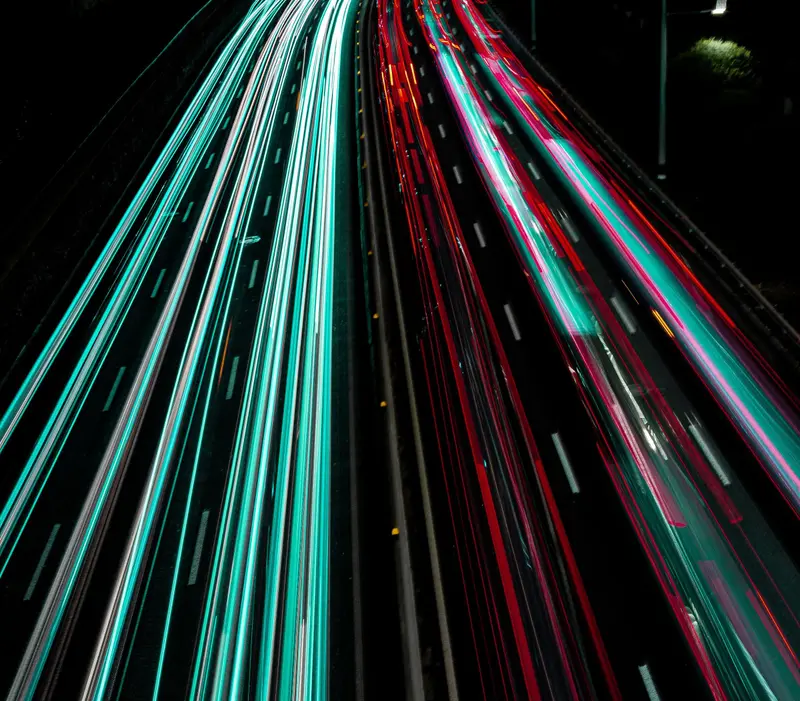 Long-exposure light trails of traffic on a multi-lane highway at night